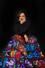 woman resting her chin in her hand, wearing a black shirt and long colorful skirt