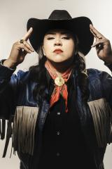 woman in a black cowboy hat, red lipstick, and a black shirt, with a red bandana tied around her neck