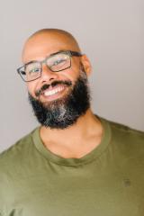 Joshua Reuben Silverstein head shot wearing a green shirt and thick-rimmed glasses.