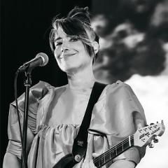 Kathleen Hanna with a microphone and guitar.
