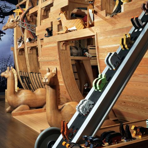 Image of the Noah's Ark exhibition build from wood and craved animals showing a conveyer belt that transports small animals up the ark