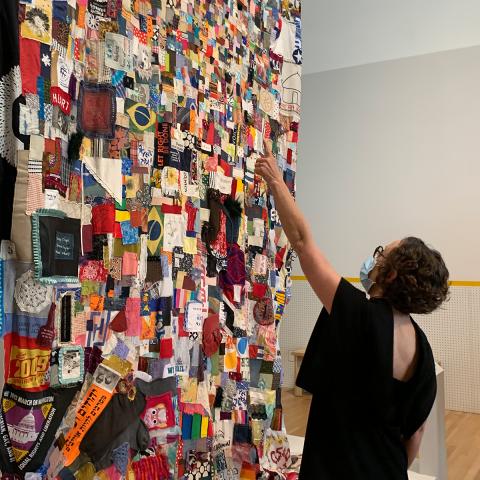 Visitor pointing out a fabric square in a big quilt with many patchwork designs