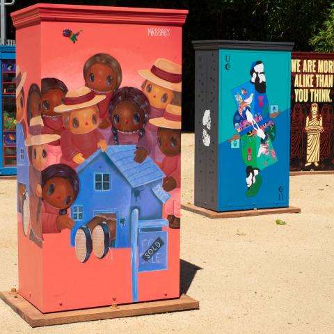 Three colorfully painted boxes installed in a park.
