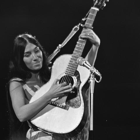 Buffy Sainte-Marie, musician, pictured playing an acoustic guitar in black and white