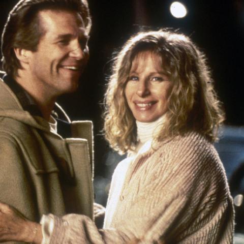 Still from the movie showing Jeff Bridges and Barbara Streisand holding each other and looking toward the camera on a street at night