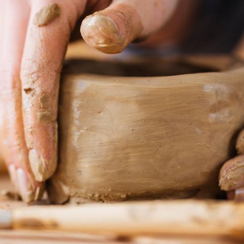 Hands craft a clay bowl.
