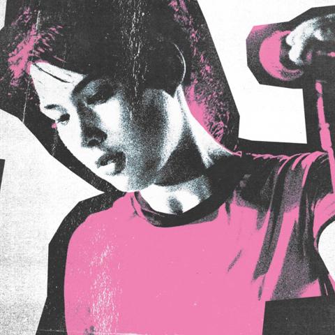 A woman standing in front of a microphone holding it next to the words The Punk Singer in script.