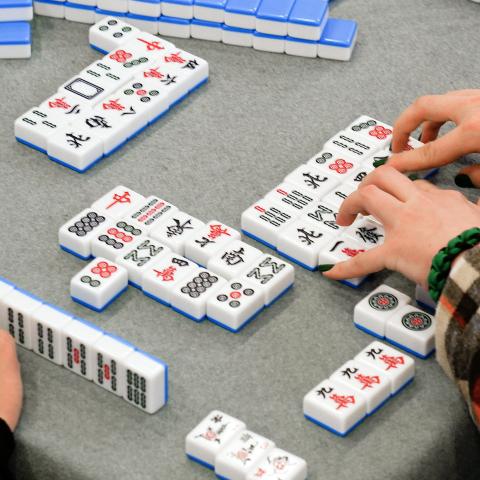 A table set up with colorful tiles and people playing Mahjong.