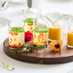 Several glasses of colorful, fruity mixed drinks on top of a round wooden serving board
