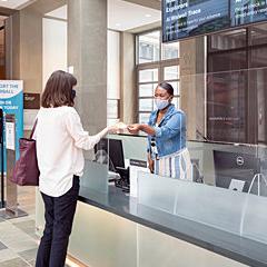 Woman behind ticket desk handing ticket to Woman with a boy standing behind her