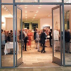 people standing inside an exhibition with art on the walls