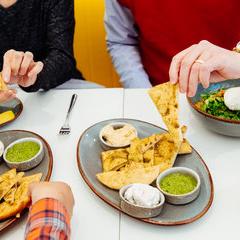 people sharing pita chips with humous and guacamole 