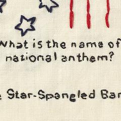 Close-up of embroidered text: 'What is the name of the national anthem? The Star-Spangled Banner' 