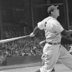 Baseball umpire, catcher and batter all looking up and toward the distance; the batter has just swung the bat