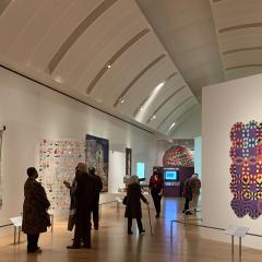 Installation photo of Fabric of Nation exhibition with visitors in gallery