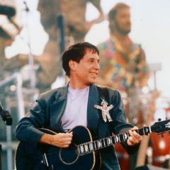 Paul Simon at a concert strumming a guitar