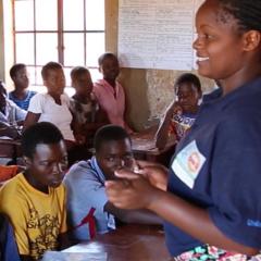 a female teacher standing in front of a class of students