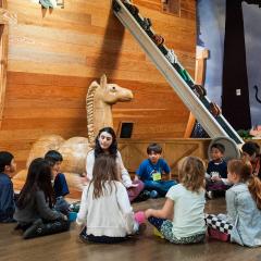 A group of young students sitting in a circle with an adult at the entrance to Noahs Ark