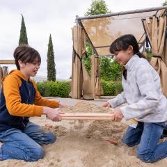 Two children uncovering objects buried in sand