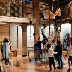 A phot of children playing inside Noah's Ark at the Skirball in the climbing ropes section of the exhibition. 