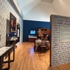 Gallery view of RECLAIMED with people engaging with cases and art work