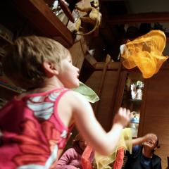 A group of young children throwing colorful scarfs in the air and dancing around.