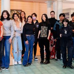 A group of teenagers posing in a group inside a gallery.