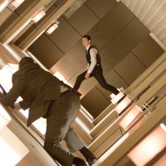 Still from the film Inception showing two men walking through a rotating hallway.