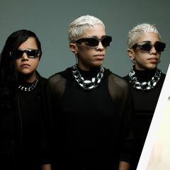 Three band members in all black with large silver chains and sunglasses poses. Next to that photo a photo of four men in a band posing in the same shirt.