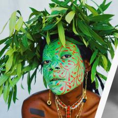 A portrait of a musical artist with a green mask on and leaves in hair next to another band of three women posing