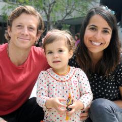 A mom, dad, and daughter smile for a photo