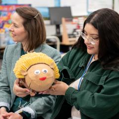A teacher holds up an animal made of different materials in a classroom