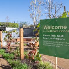 A green sign with white text welcomes visitors to the Bloom Garden.