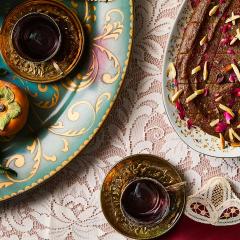 Persian food is displayed on plates on a tables covered in white lace.
