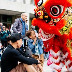 A child stares excitedly at a red dragon puppet in the courtyard.