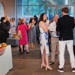 A room of people talking in small groups with appetizers and drinks.