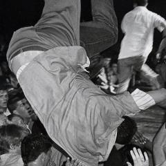 A man stage dives into a crowd of people at a concert.
