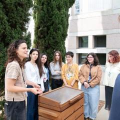 Garden Fellow stands beside compost and teaches students about recycling.