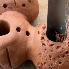 A ceramic sculpture in clay being worked on with a tool.