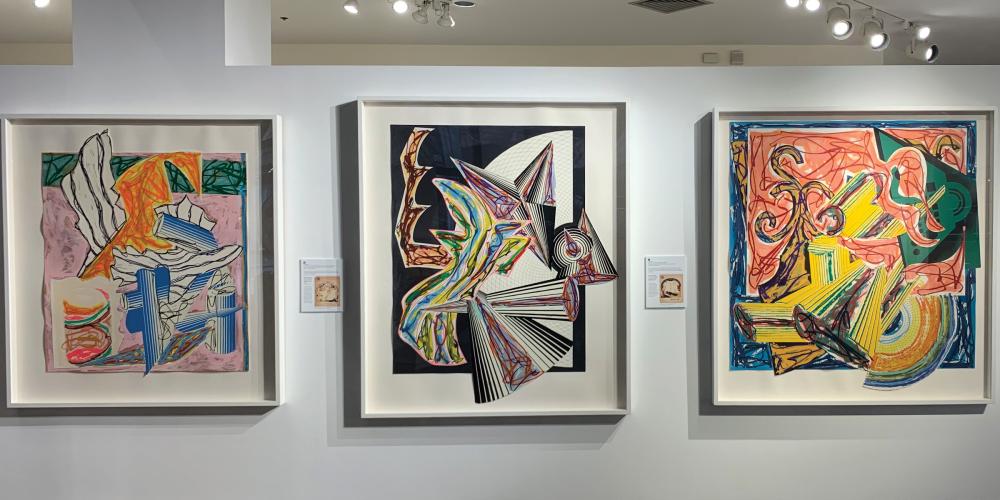 Three large, colorful prints depicting the story in the song Had Gadya hang side by side on a gallery wall