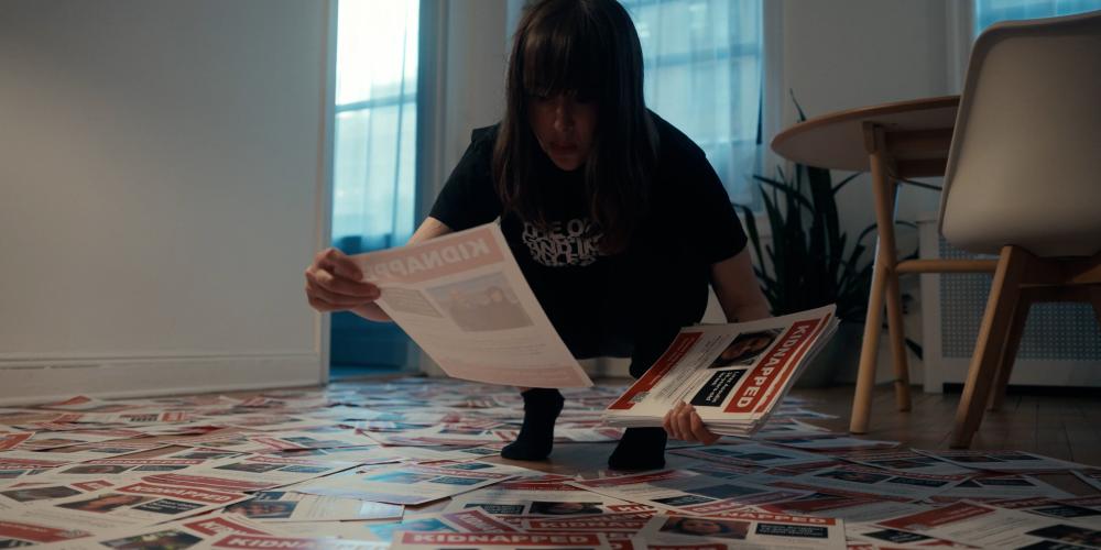 Still from TORN with Nim Shapira looking at posters on the ground.