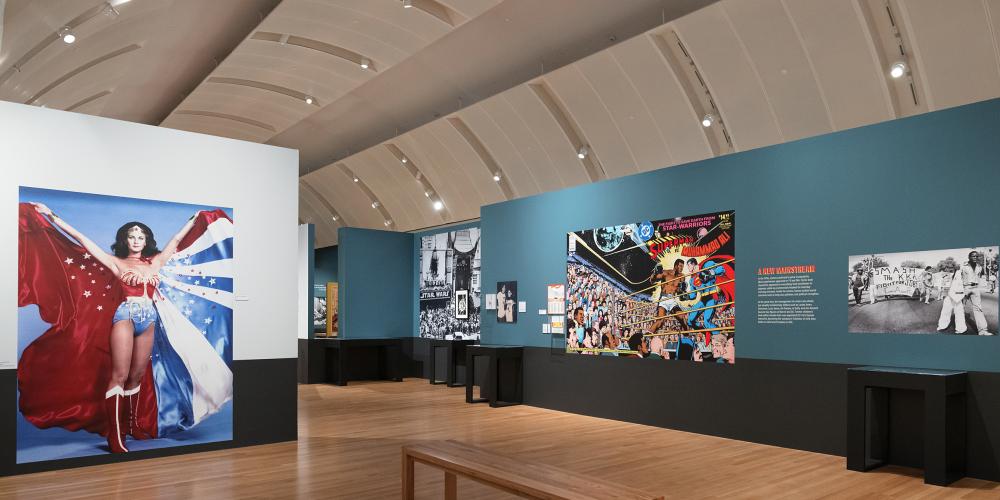 A wide gallery shot with a large mural of Wonder Woman and another with Superman.