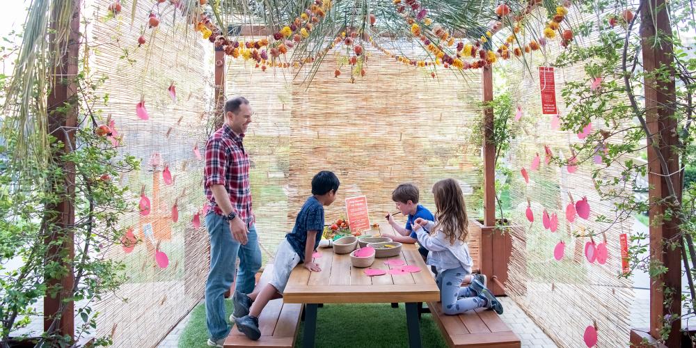 A family gathered under a sukkah made from natural materials.